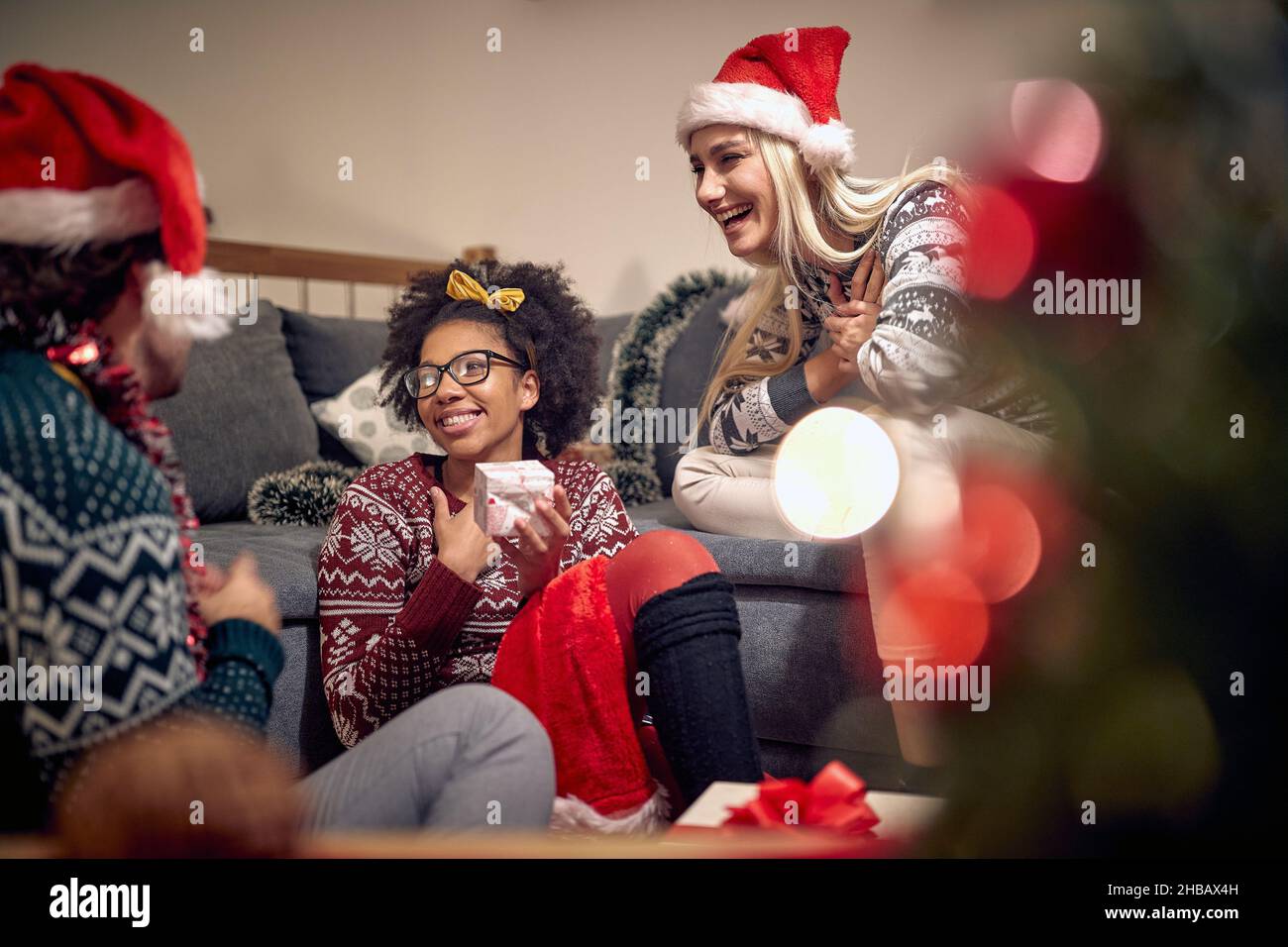 A girl is touched by a present she got from friends during New Year party in a festive atmosphere at home. Christmas, New Year, holiday, party Stock Photo