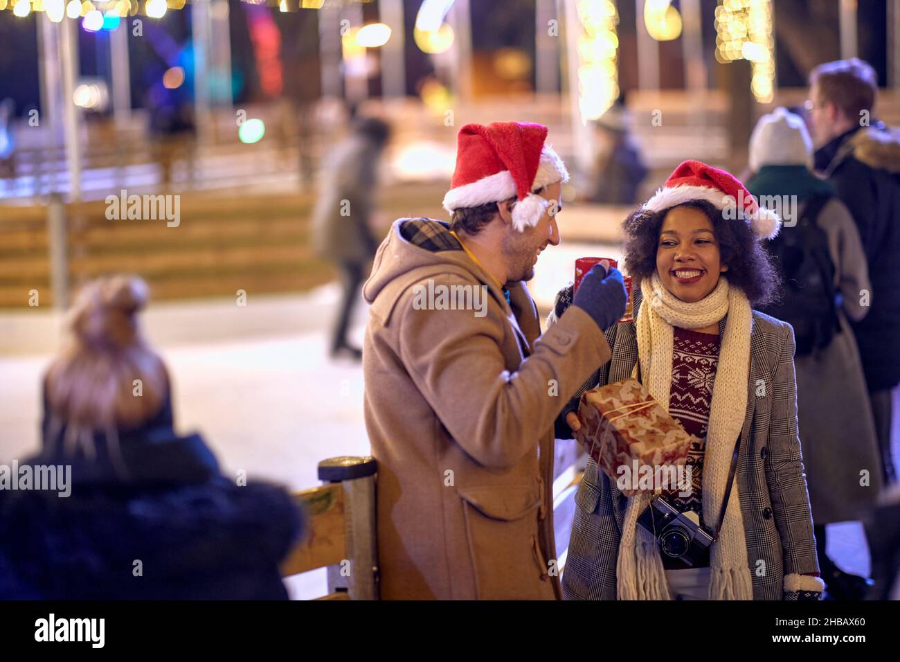 Happy man and girl  enjoying at christmas festival on a snowy weather and drink tea Stock Photo