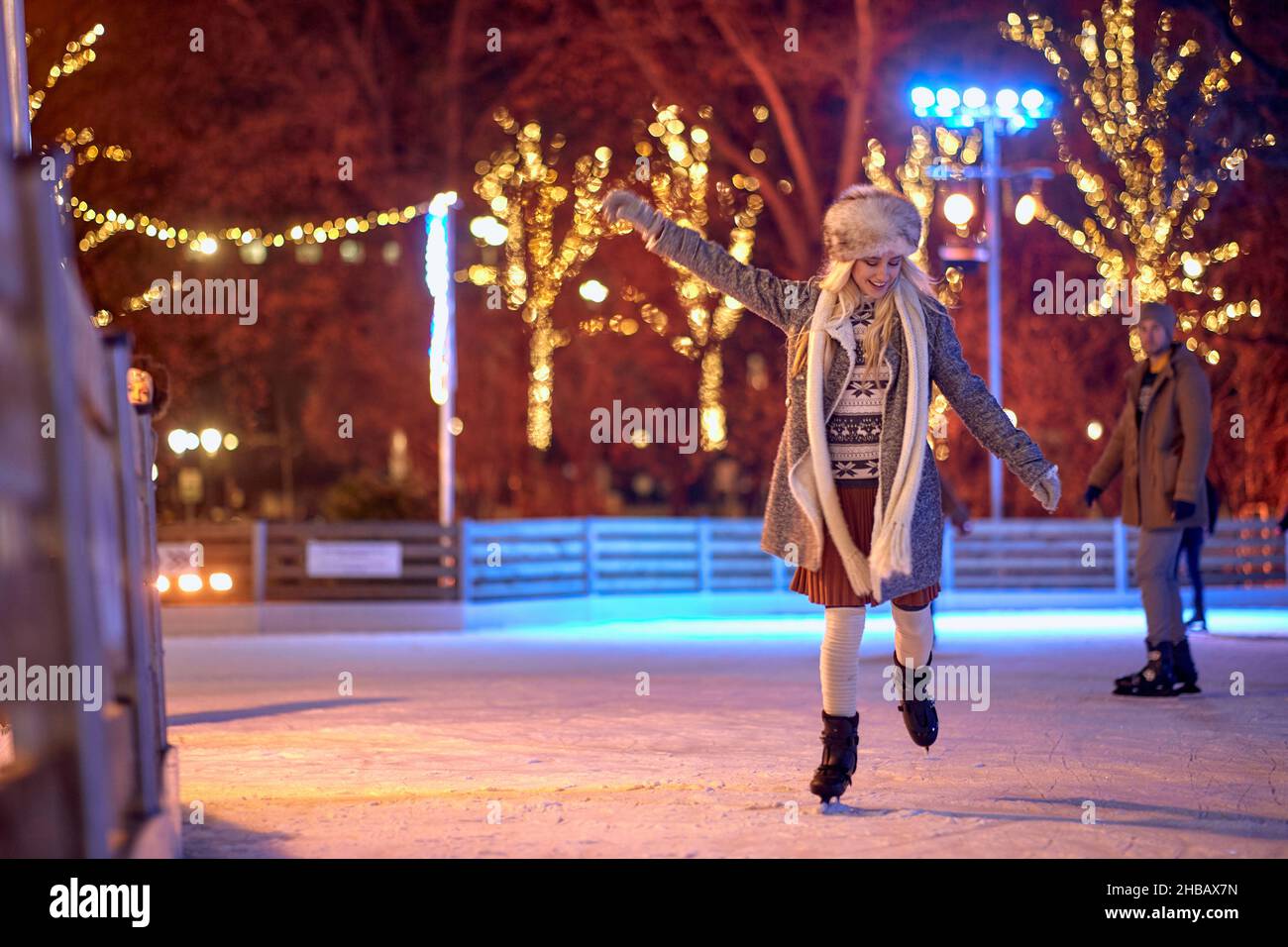 Happy female ice skating alone at night; Winter joy concept Stock Photo