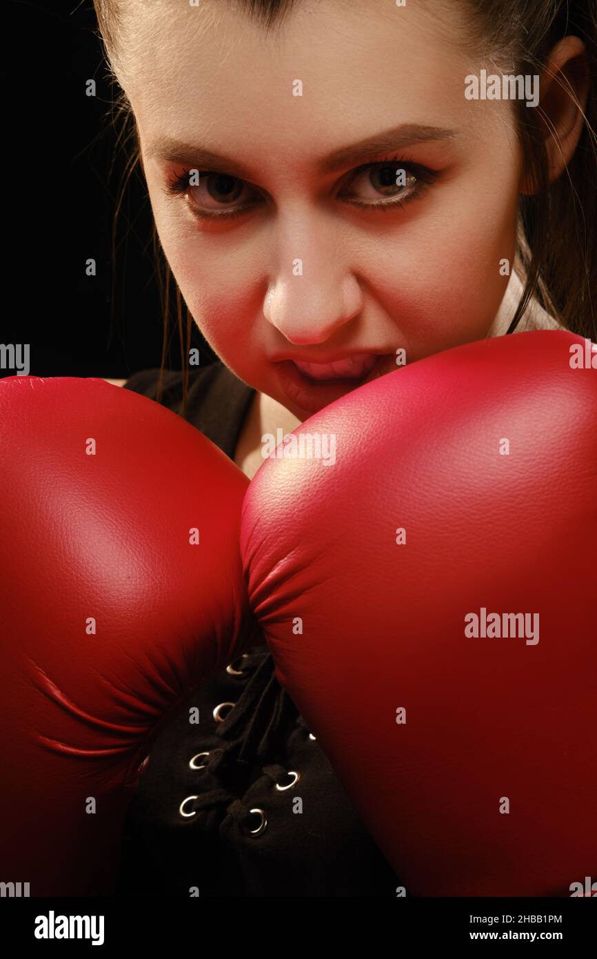 Muay Thai female boxer in attack pose. Fitness young woman boxing training on black background Stock Photo