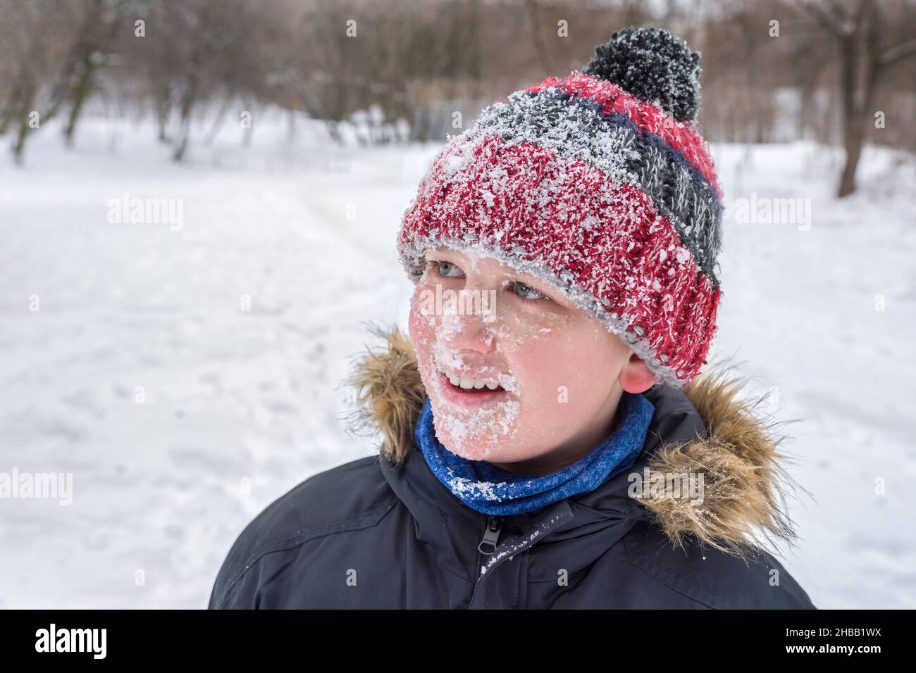 Portrait of a happy happy boy in winter on a background of snow. All face in the snow. Stock Photo