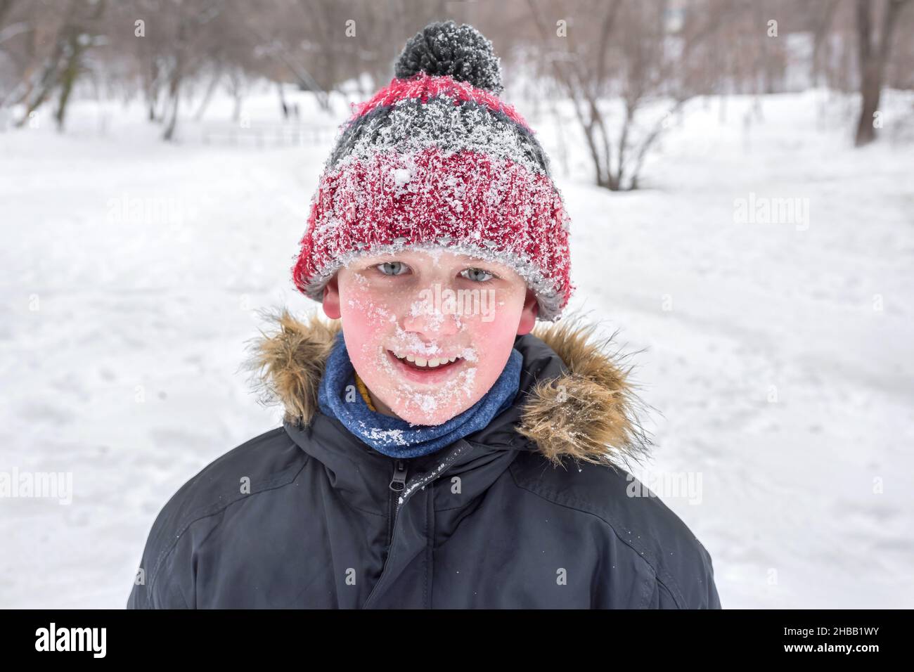 A boys portrait in winter time. The whole face in the snow. Stock Photo