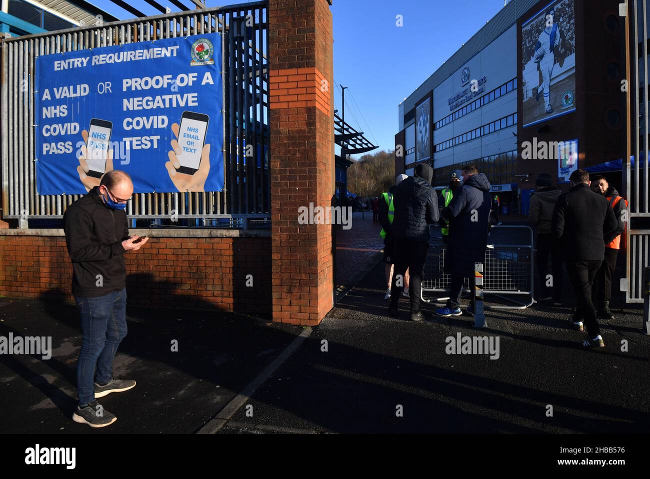 A fan looking at their mobile phone next to a Covid Pass sign outside the ground ahead of the Sky Bet Championship match at Ewood Park, Blackburn. Picture date: Saturday December 18, 2021. Stock Photo
