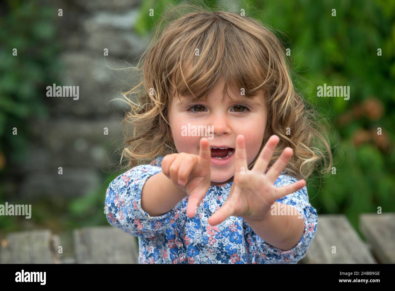 Two Year Old Girl, blonde, outdoors, counting on her fingers Stock Photo