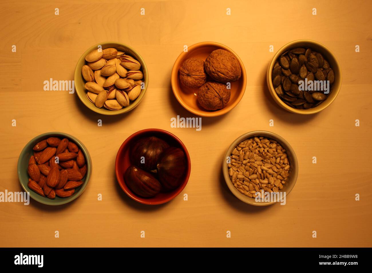 Six ceramic bowls containing whole nuts and seeds. Concept for health