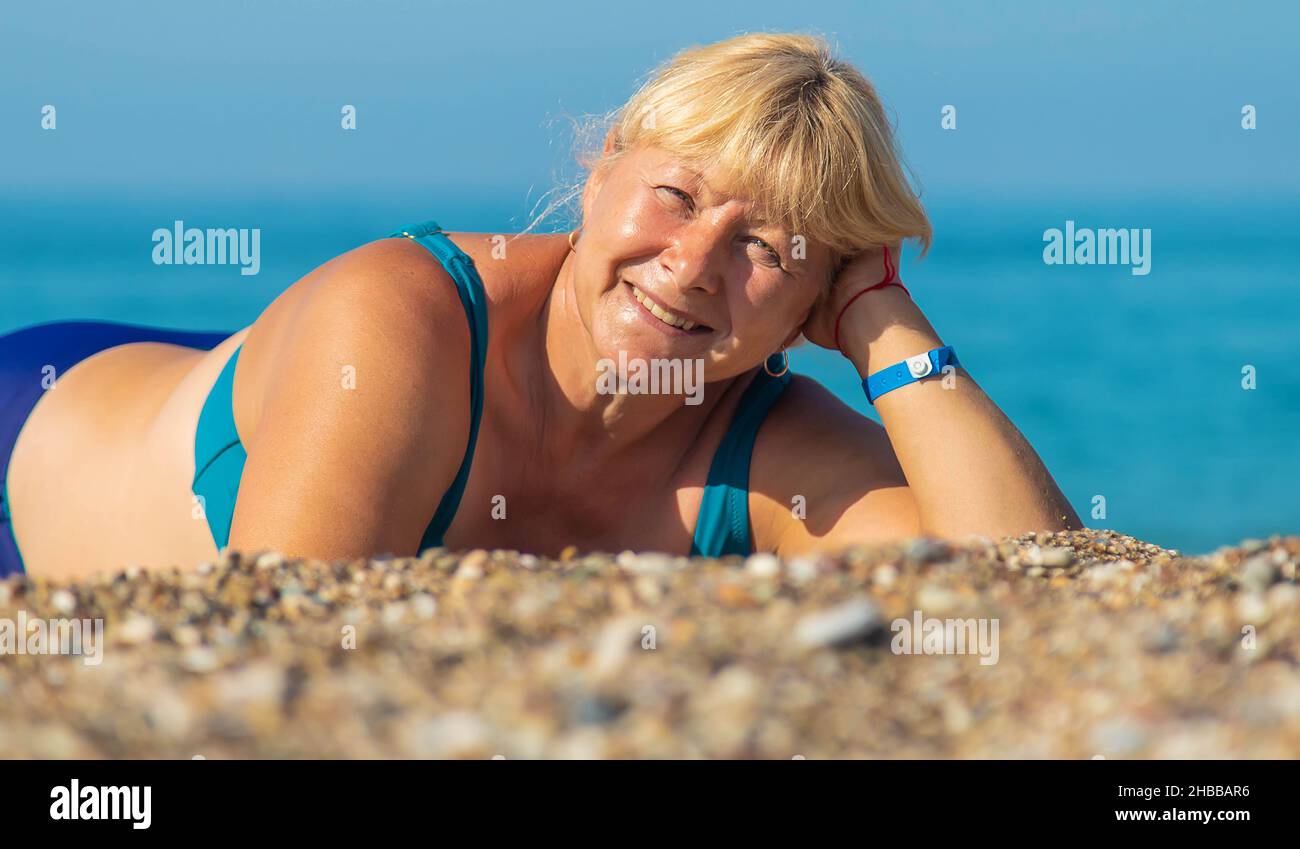 An elderly woman is resting on the beach. Selective focus. Stock Photo
