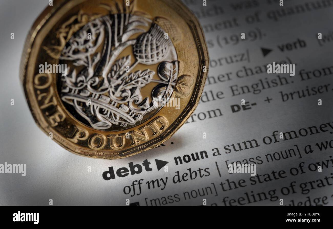 DICTIONARY DEFINITION OF THE WORD DEBT WITH ONE POUND COIN RE MORTGAGES ECONOMY HOUSEHOLD BILLS ETC UK Stock Photo
