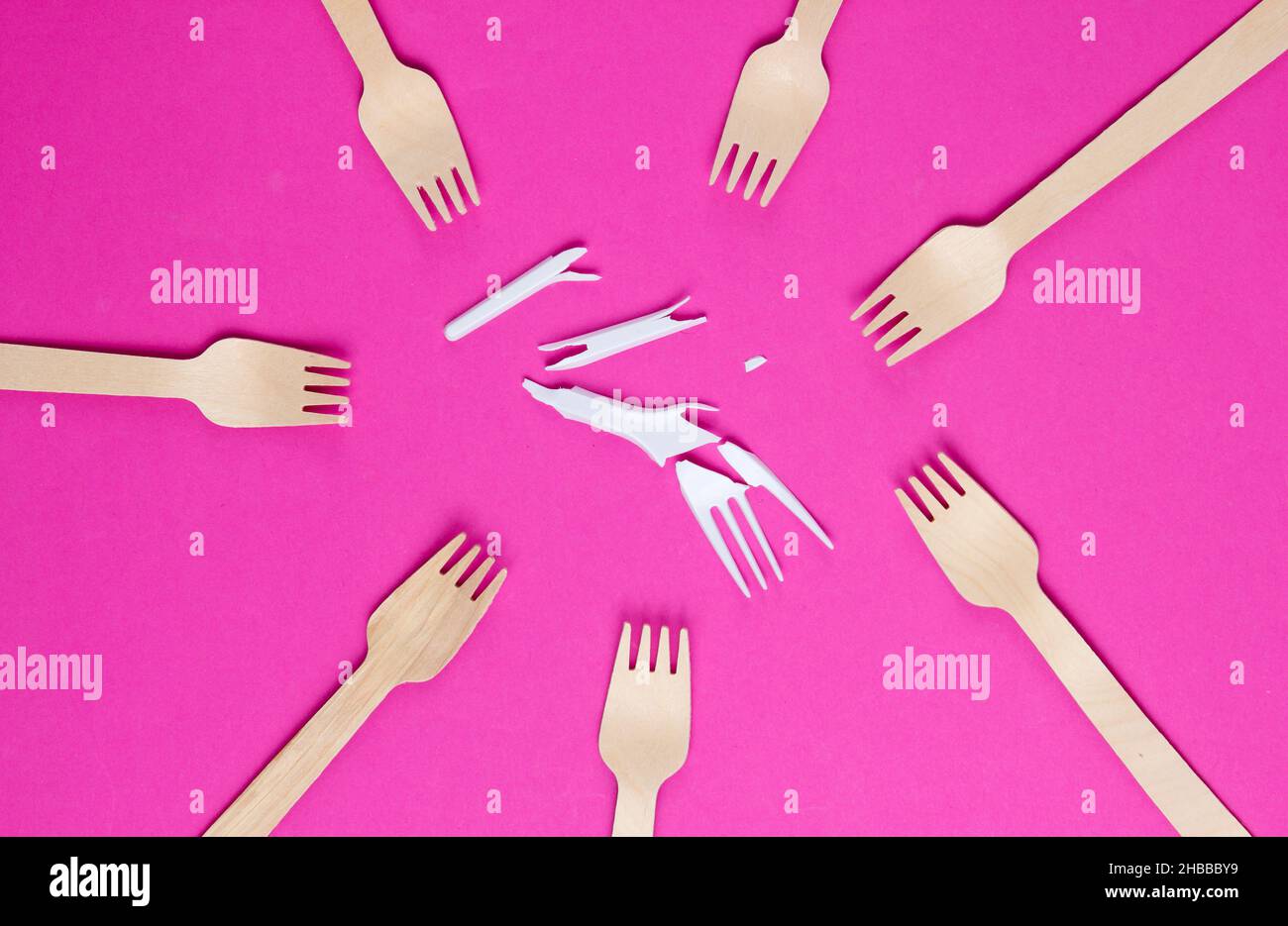 Minimalistic ecologically clean still life. Pop Art. Broken plastic fork among many wooden forks on pink background. Cutlery made from natural materia Stock Photo