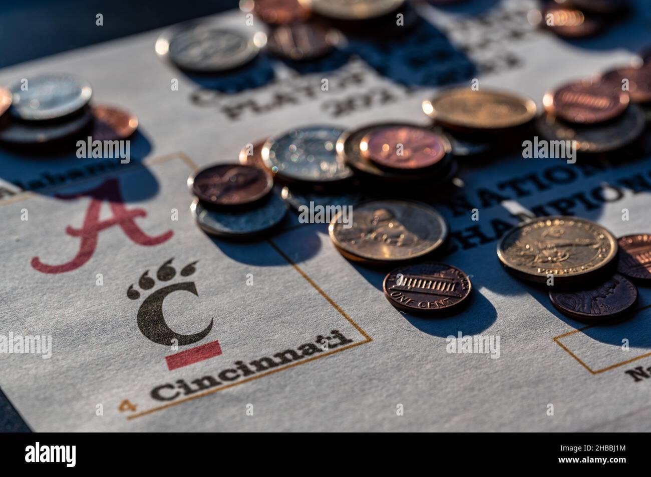 Tiffin, Iowa, USA - 12.2022 - Selective focus on 2021-2022 College Football Playoff Bracket with scattered coins. Stock Photo