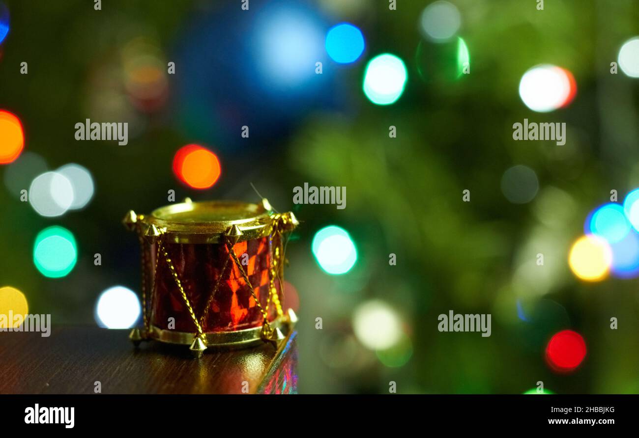 Closeup of a tiny drum Christmas ornament with a bright glowing tree in ...