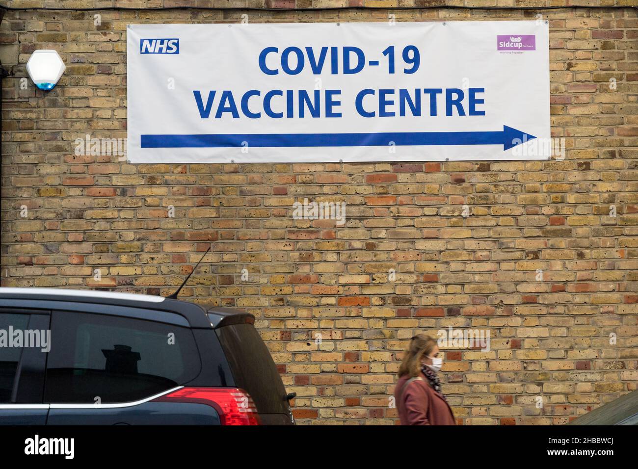 Poeple in face mask walk past towards NHS vaccine centre offering