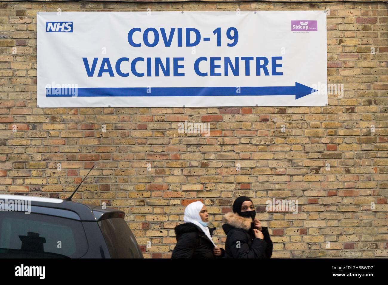 Poeple in face mask walk past towards NHS vaccine centre offering booster dose and vaccine