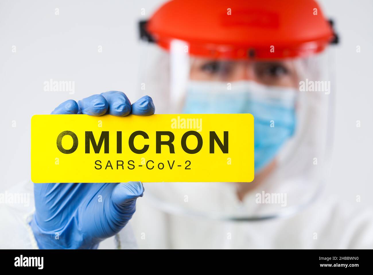 Genetic mutation of Coronavirus causing new COVID-19 cases,medical worker wearing PPE and face shield holding yellow board SARS-CoV-2 OMICRON sign Stock Photo