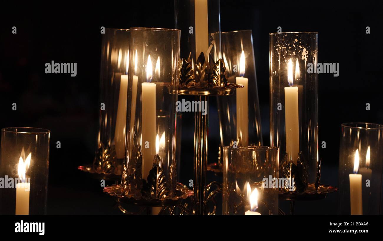 Lit candlesticks in glass sconces in a darkened room Stock Photo