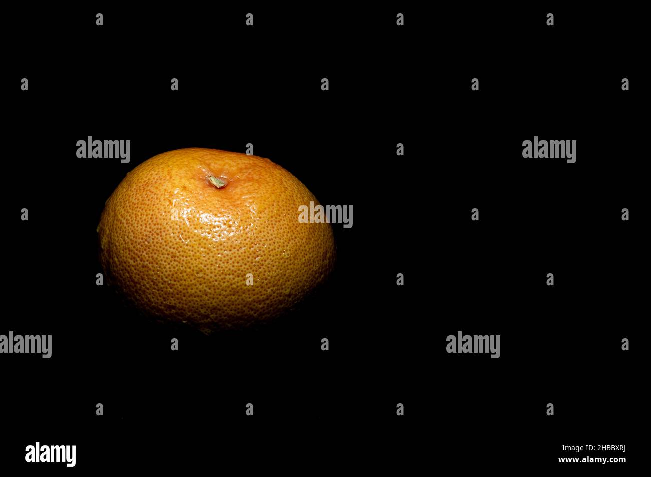 ripe grapefruit with small water droplets on a black background Stock Photo