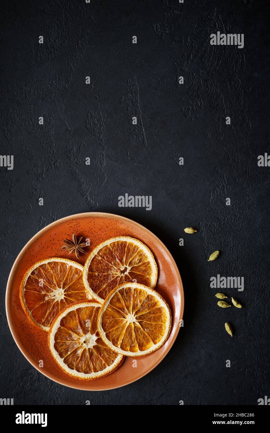 Plate with dried orange slices with badjan and cardamom on black slate background with copy space Stock Photo