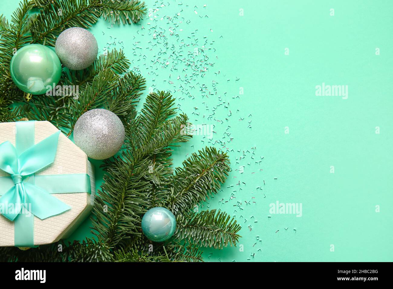 Christmas balls, fir branches and gift box on green background Stock ...