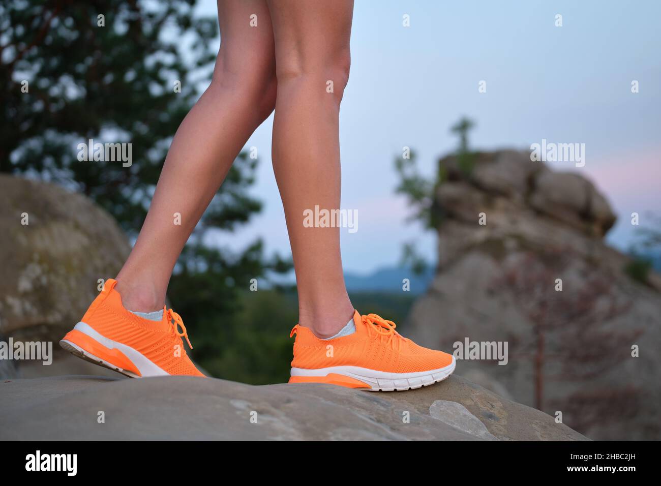 Closeup of young woman slim legs in bright orange sneaker shoes walking on mountain hiking trail in summer. Active way of life and exercise on fresh a Stock Photo Alamy