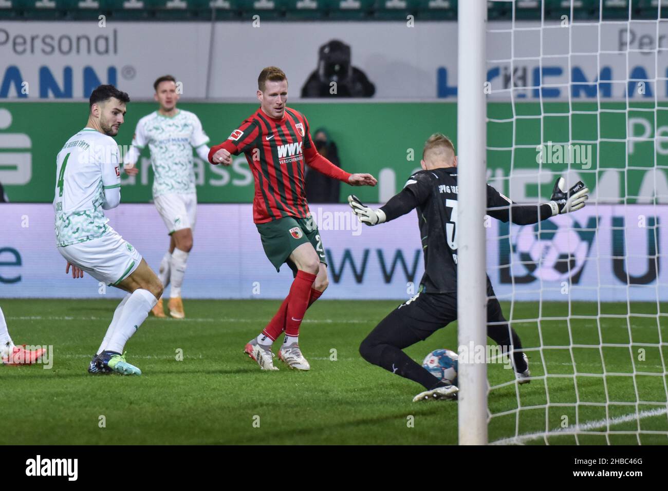 Germany ,Fuerth, Sportpark Ronhof Thomas Sommer - 18 Dec 2021 - Fussball, 1.Bundesliga - SpVgg Greuther Fuerth vs. FC Augsburg  Image: (fLTR) Maximilian Bauer (SpVgg Greuther Fürth,4), Andre Hahn (FC Augsburg, 28); GK Sascha Burchert (SpVgg Greuther Fürth,30) blocking a close-ranged shot.  DFL regulations prohibit any use of photographs as image sequences and or quasi-video Credit: Ryan Evans/Alamy Live News Stock Photo