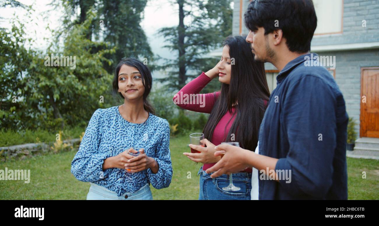 Shallow focus of young adult Indian friends drinking and talking during a party in a garden Stock Photo