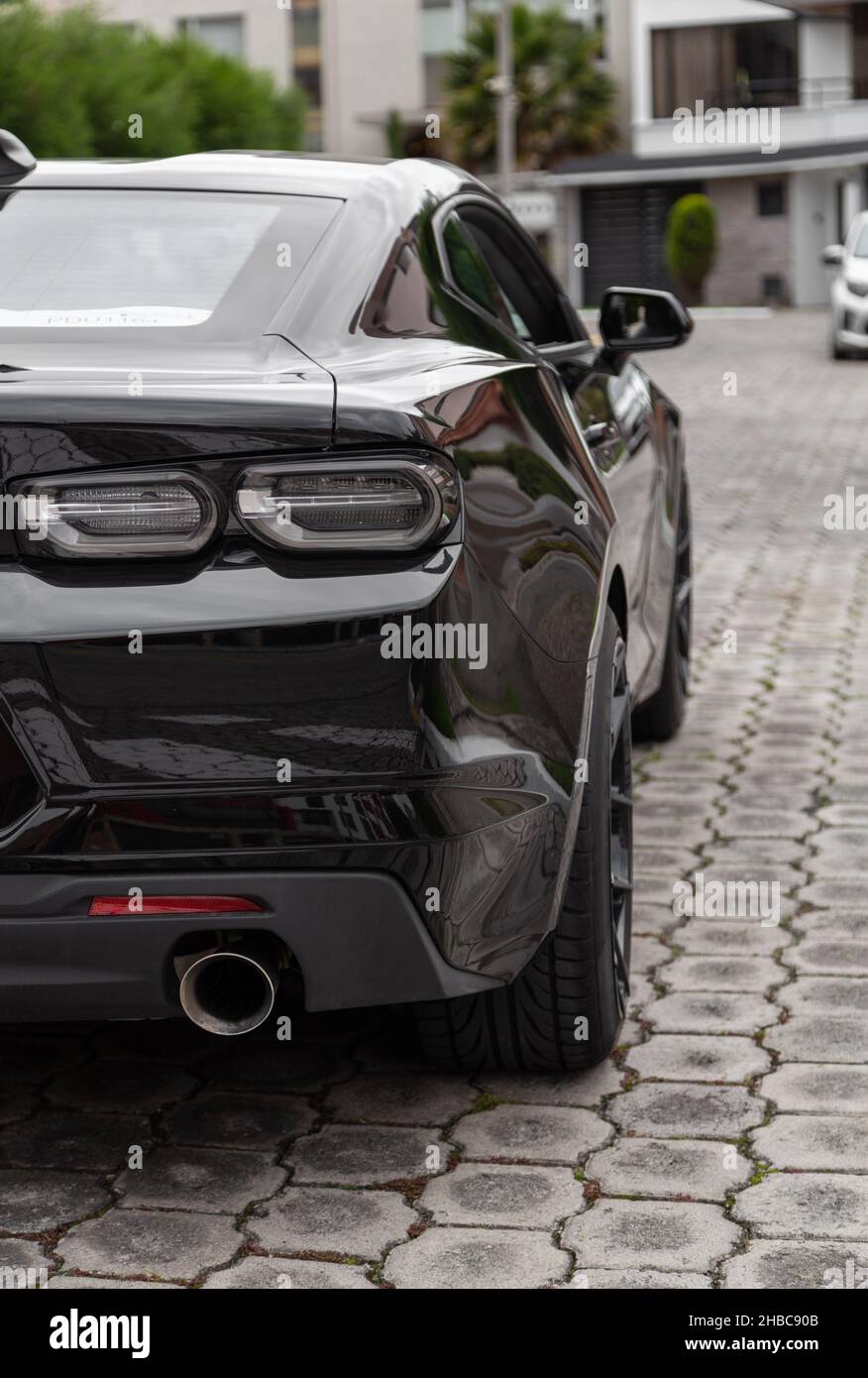 details of the rear of a black sports car, showing the exhaust pipe and taillights, means of transport in the city, lifestyle in the city Stock Photo