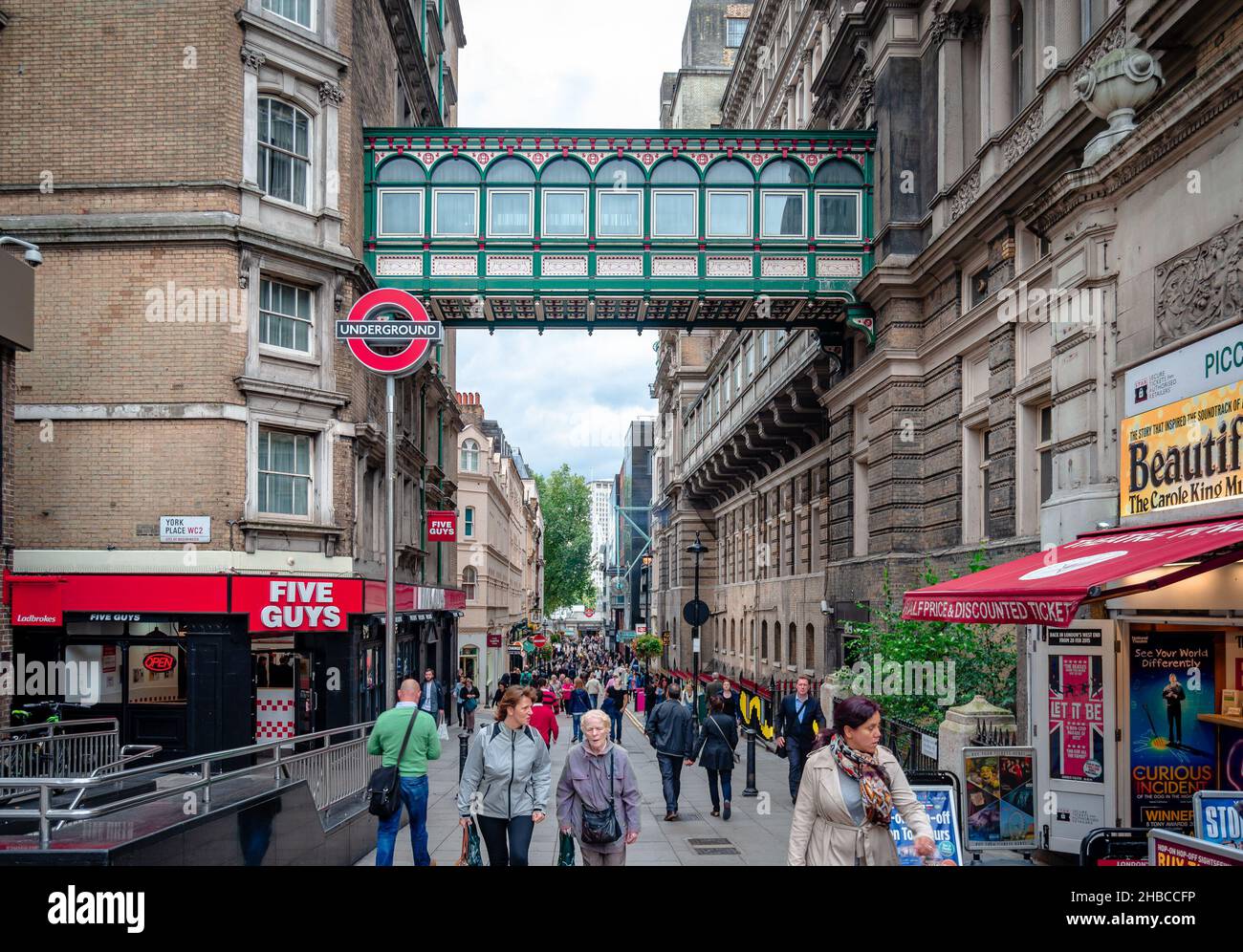 London, UK - September 4 2015: View of the crowded pedestrianised part of Villiers St in Charing Cross, with the overlooking railway station passage. Stock Photo
