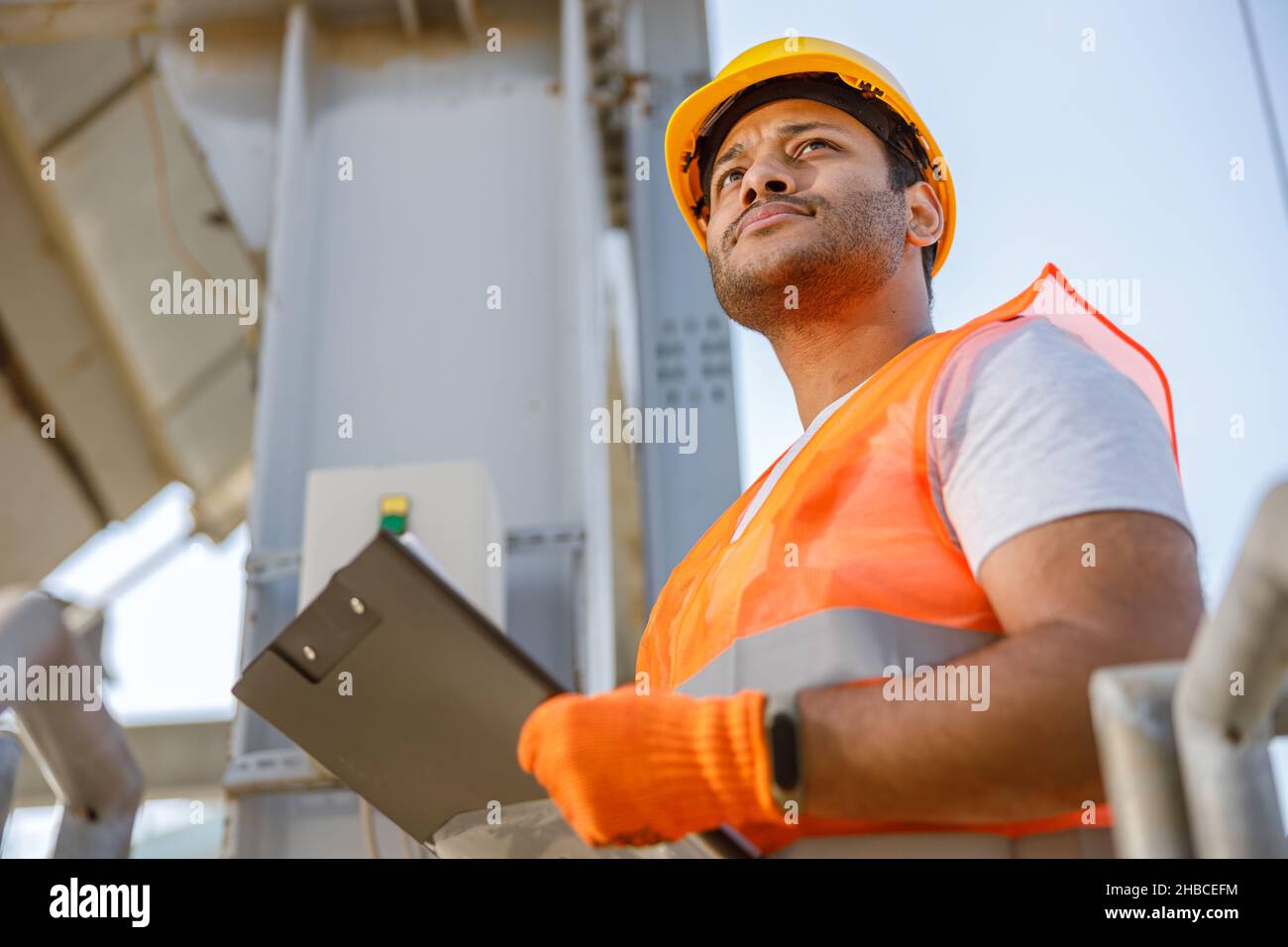 Serious young worker standing at industrial site Stock Photo