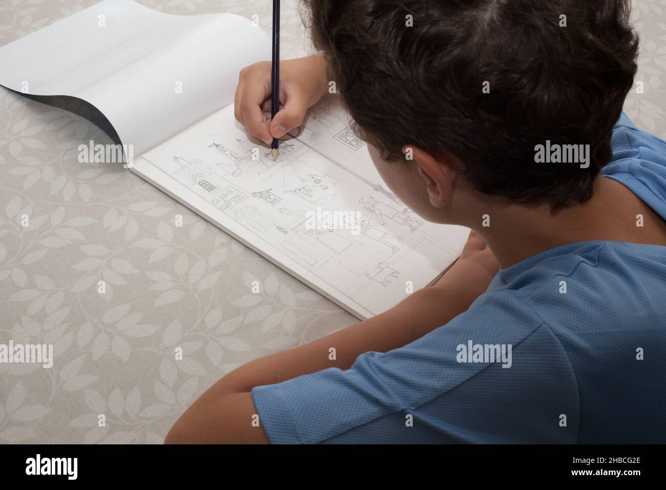 A boy sketching out a drawing of a seaside town, taken 13th of August 2020 in Wool, Dorset, UK Stock Photo