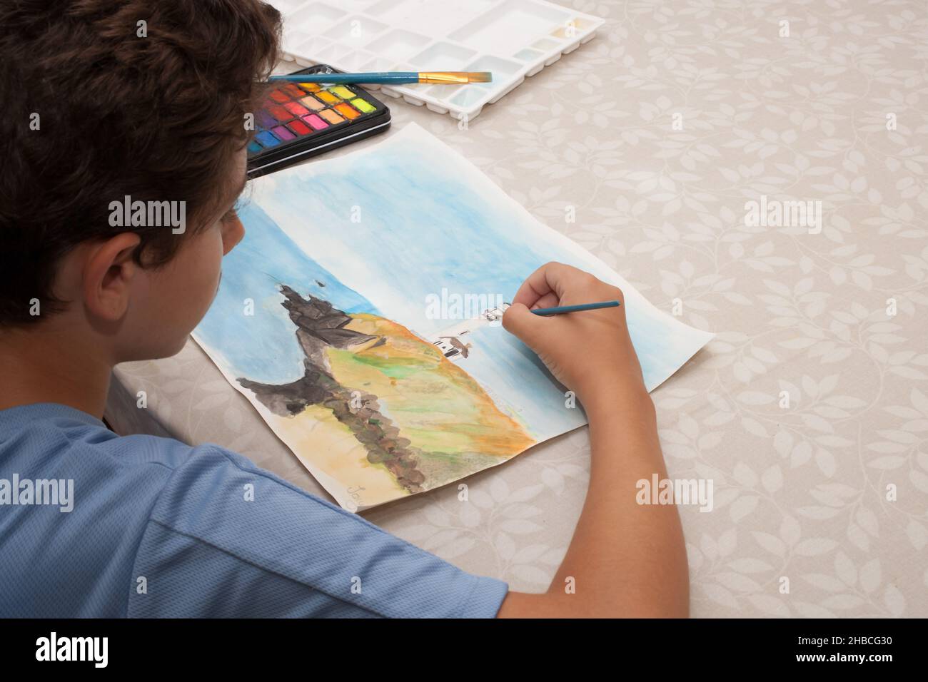 A boy painting a picture of a lighthouse with watercolours, taken on the 13th of August 2020 Stock Photo