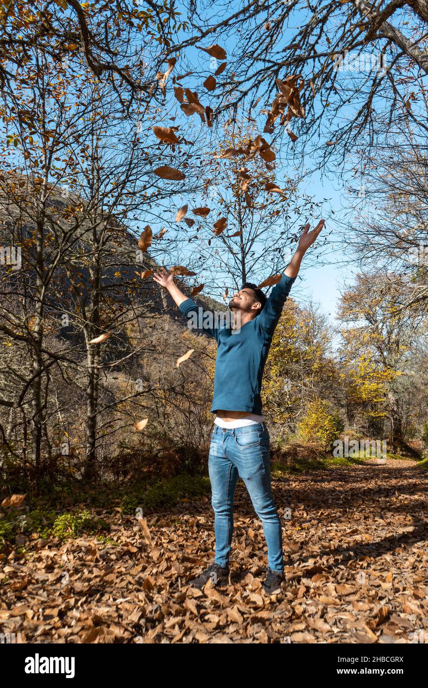 young man plays with yellow leaves falling down. vertical composition Stock Photo