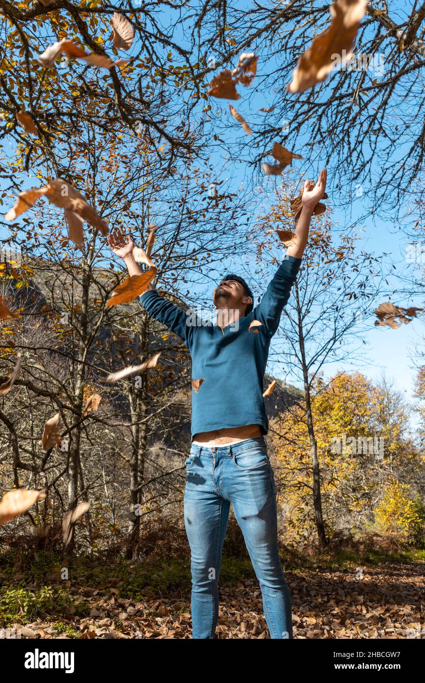 young man plays with yellow leaves falling down. vertical composition Stock Photo