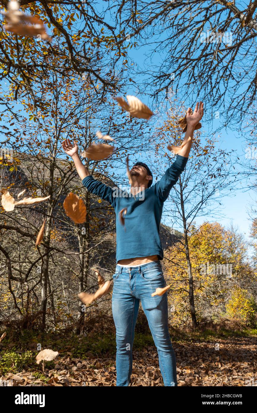 young man plays with yellow leaves falling down. vertical composition Stock Photo