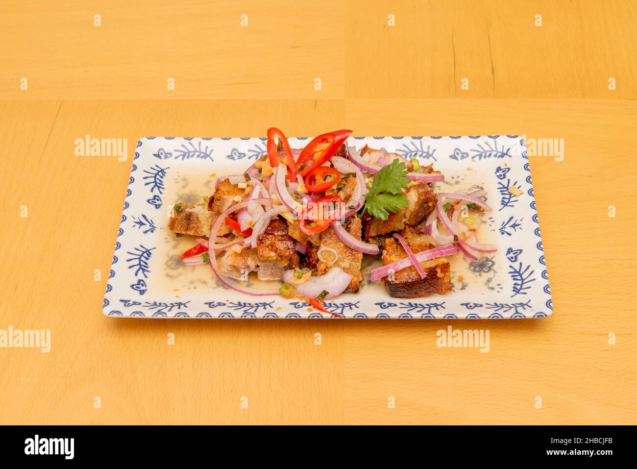 Philippine recipe of lechon ceviche with peppers and meat with raw purple onion on porcelain plate Stock Photo