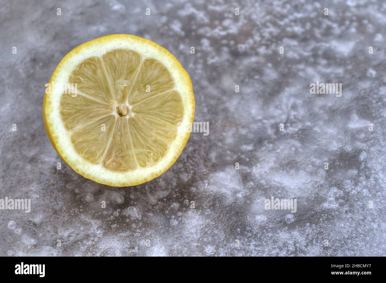 Half a lemon on an icy surface. Lemons are healthy because they contain a lot of vitamin C. Stock Photo