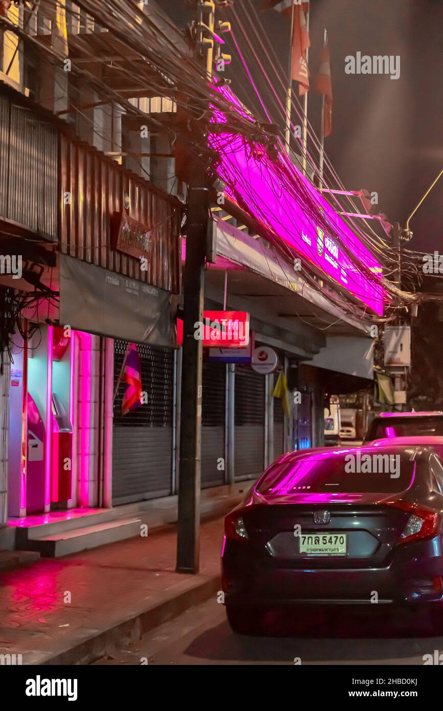 Pink neon scene. Boarded-up store and a parked car in bangkok, Thailand. Stock Photo