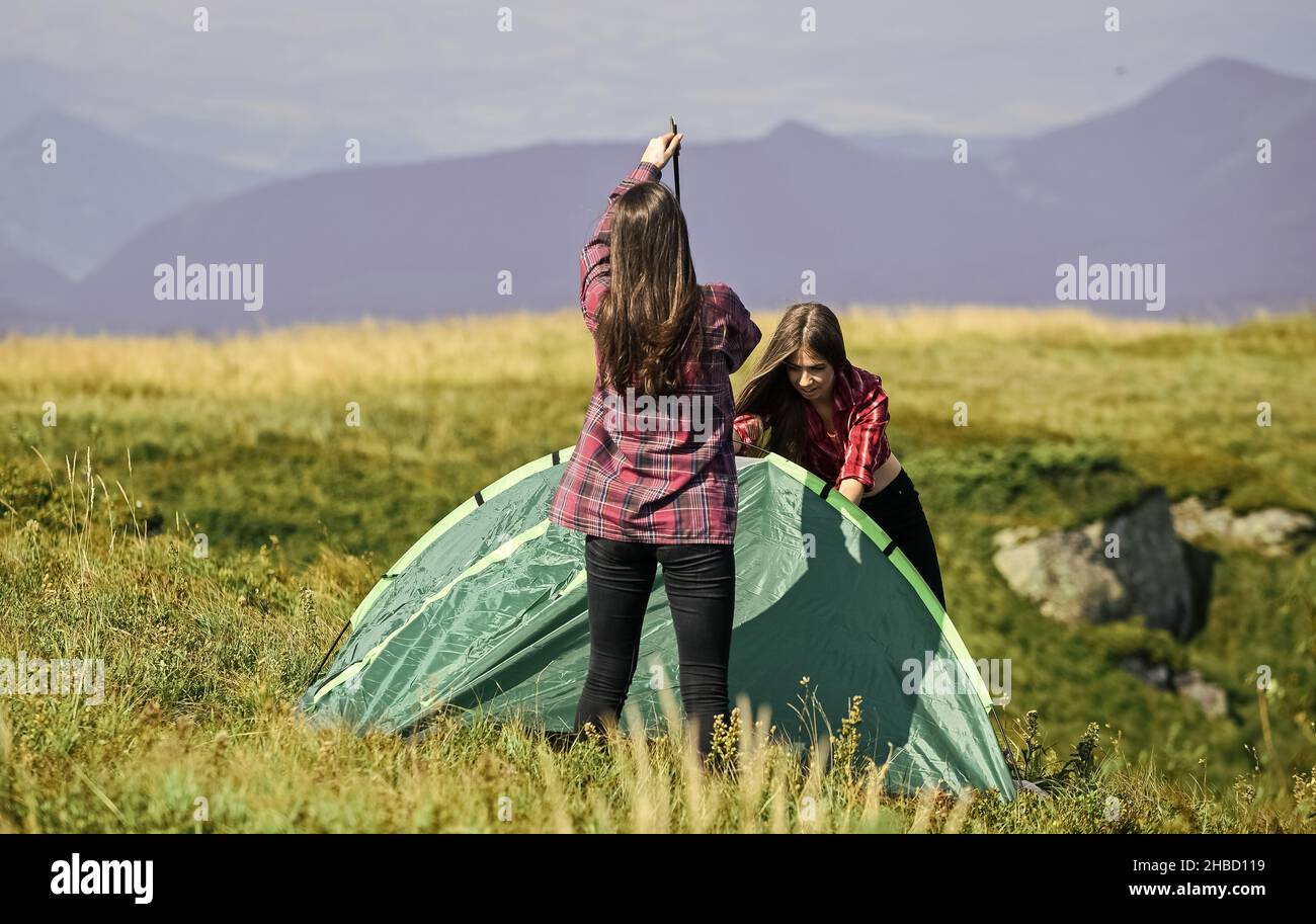 Hiking activity. Attach necessary structural components tent. Prepare for night. Girl scout concept. Camping hiking. Helpful to have partner for Stock Photo