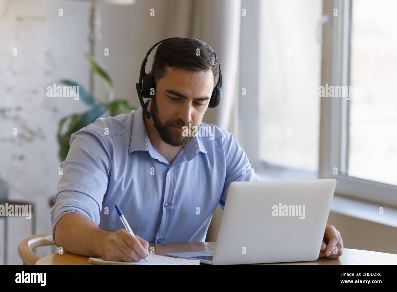 Focused young man studying distantly at home. Stock Photo