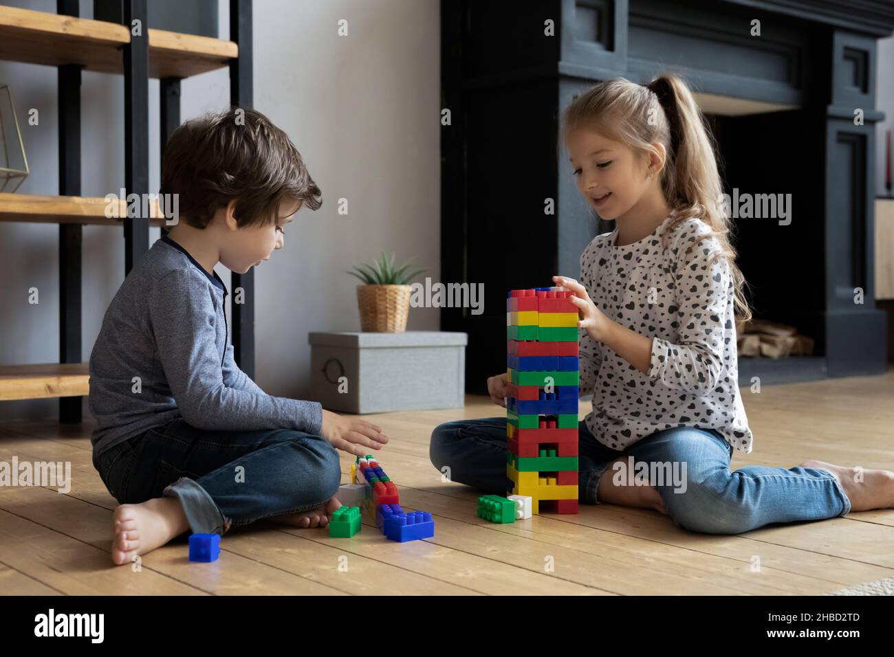 Happy sister and brother playing with colorful plastic construction toys Stock Photo