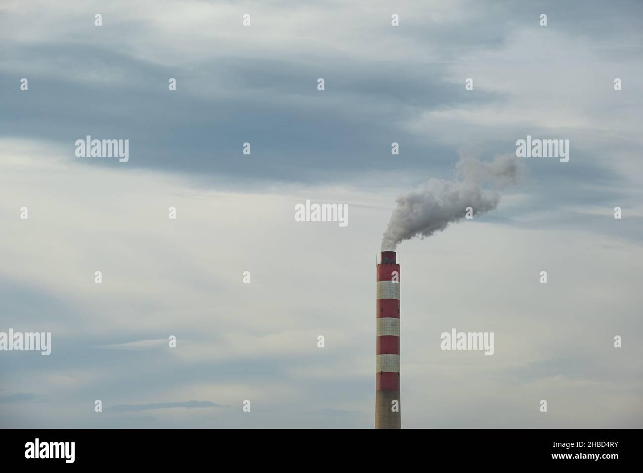 Factory chimney or tower with smoke coming out. Factory pipe pollutes the air in an industrial area. Global warming, polluted air. Stock Photo