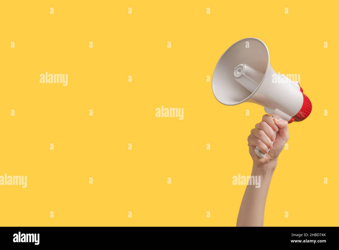 Megaphone in woman hands on a yellow background.  Copy space. Stock Photo