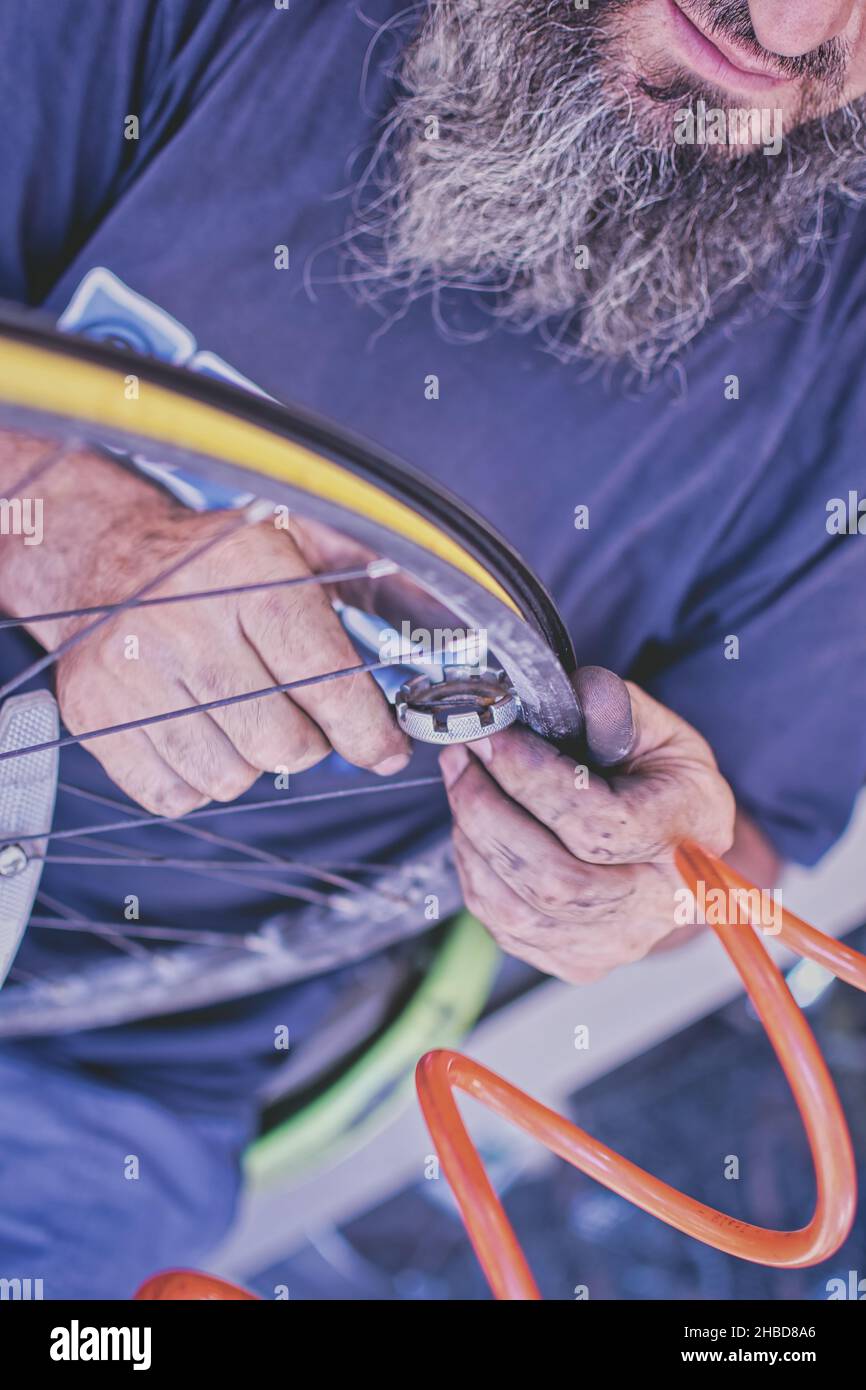 Bicycle mechanic with beard and dirty hands is tightening bicycle
