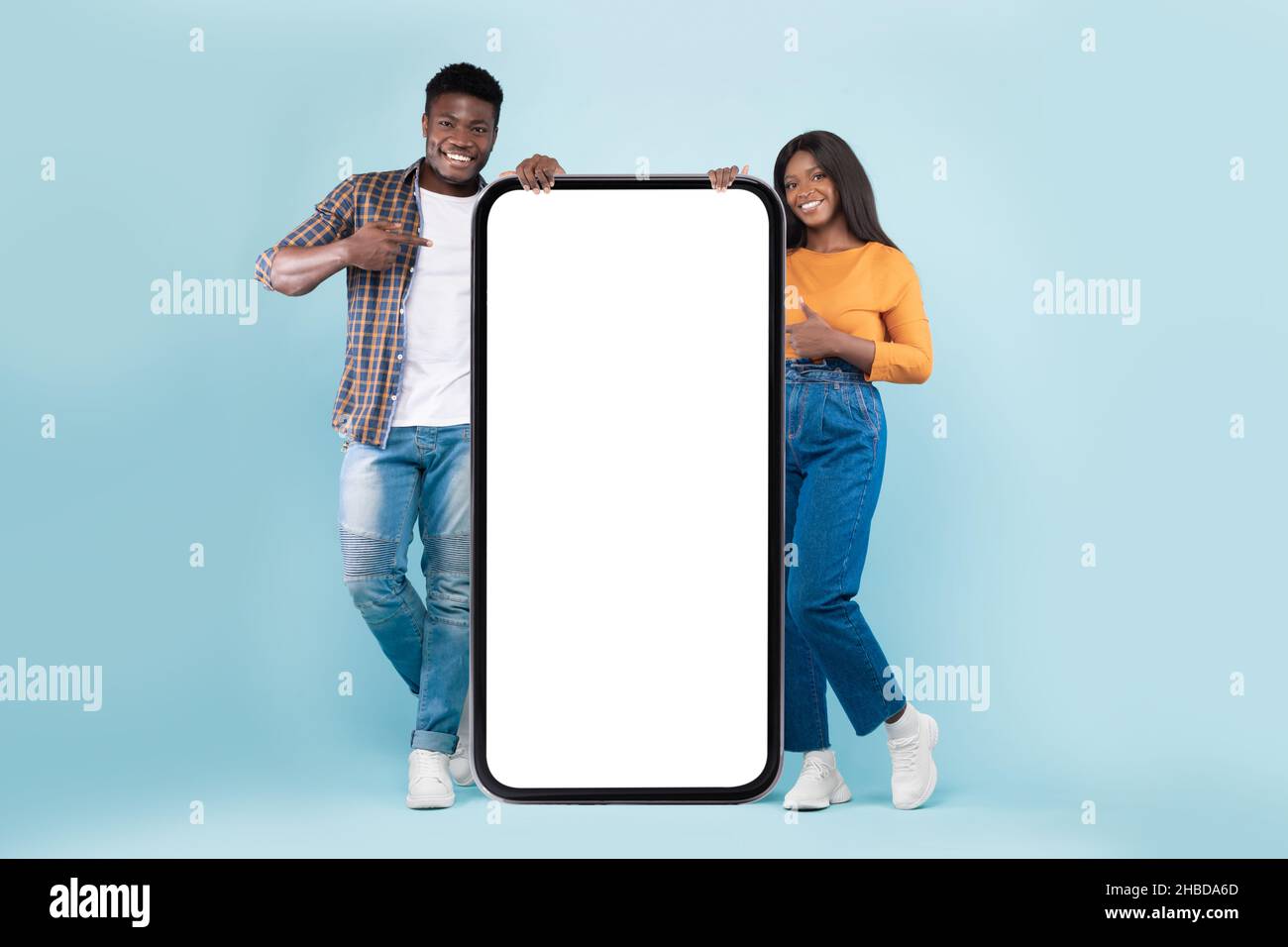 Couple showing white empty smartphone screen leaning on display Stock Photo
