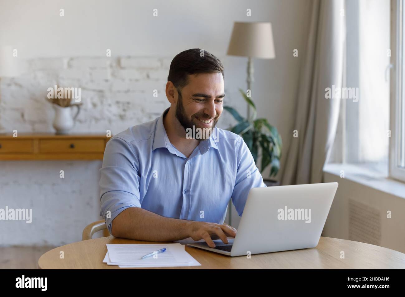Smiling millennial businessman enjoying working on computer. Stock Photo