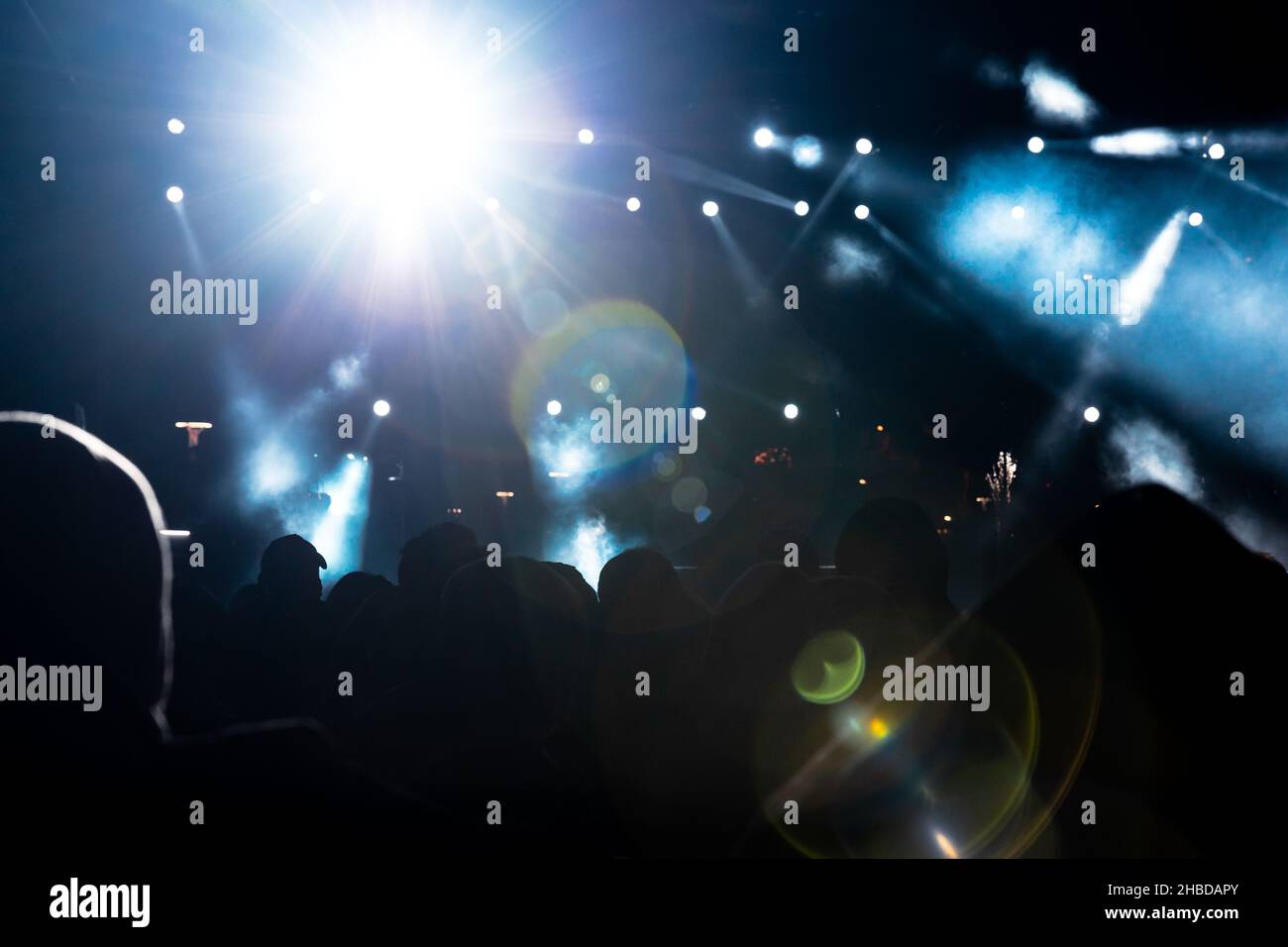 Concert background photo. Spotlight glowing and lens flares in the concert hall. Silhouette of the people. Stock Photo