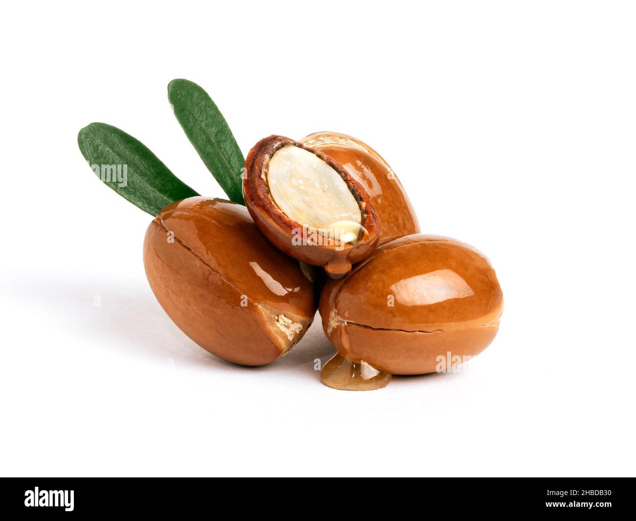 Three argan nuts with green leaves on an isolated white background