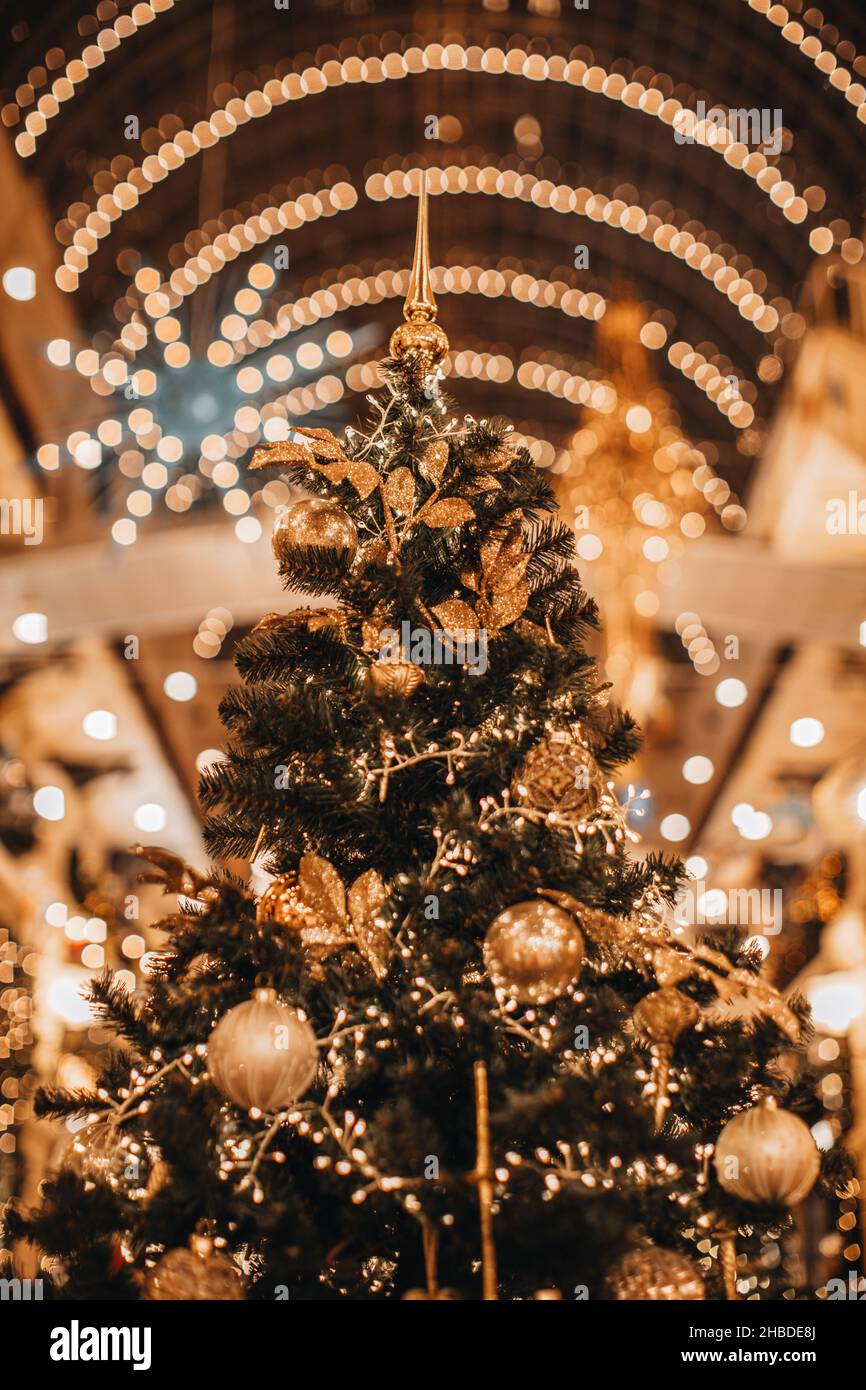 Golden magic Christmas tree decorated with glittering garland and shiny Christmas balls. New Year details, festive bokeh miracle background. winter ho Stock Photo
