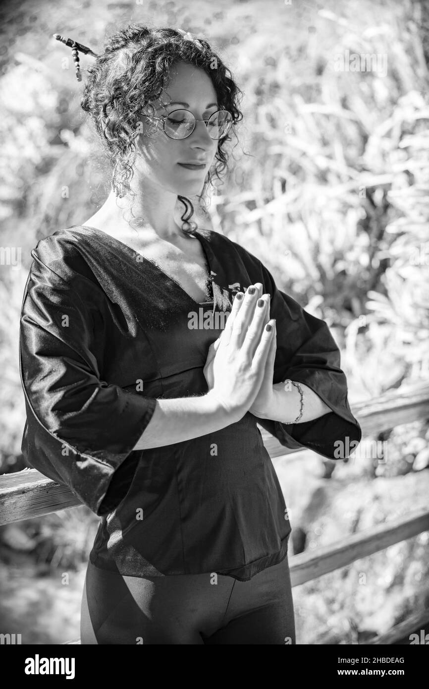 A Caucasian girl in Asian costume in a garden in grayscale Stock Photo