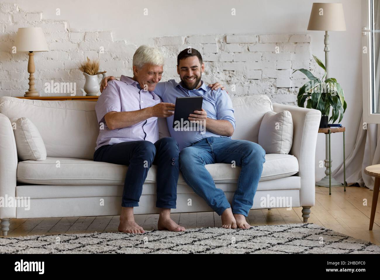 Happy young man and old father using digital tablet. Stock Photo