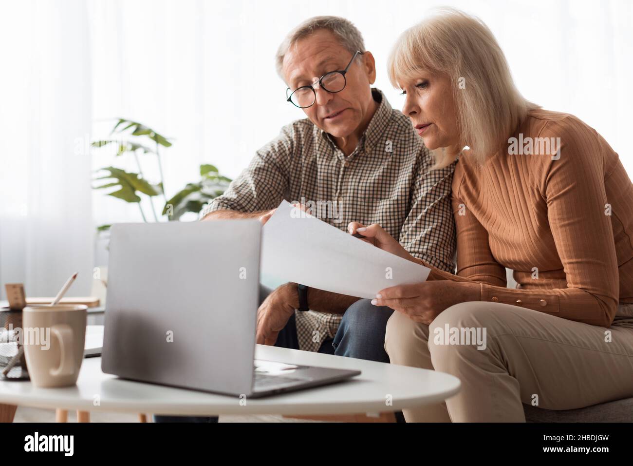 Mature Spouses Reading Papers And Documents Holding Letters At Home Stock Photo