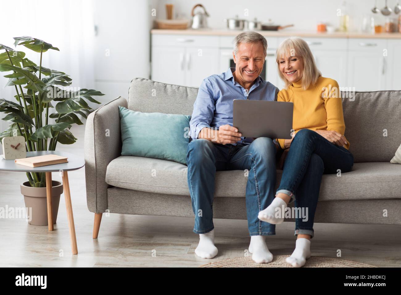 Cheerful Senior Spouses Using Laptop Watching Movie Onilne At Home Stock Photo